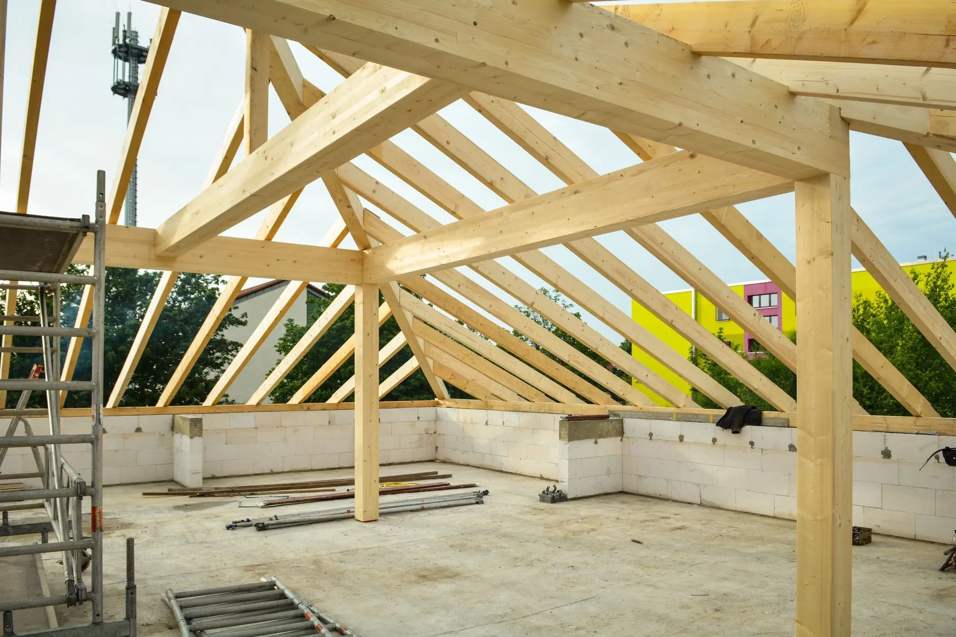 New timber roof frame of glulam posts and rafters standing open to the sky over a concrete slab.